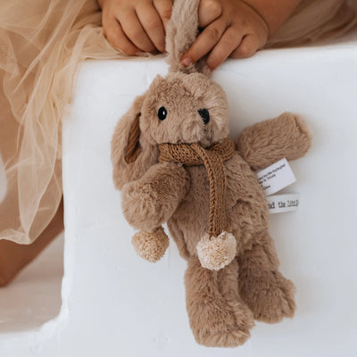 Toddler's hand holding Hugh Rabbit Mini