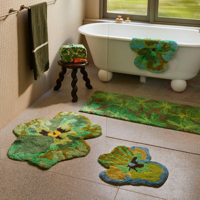 Bathroom with a white freestanding bathtub, pansy, viola green small bath mat, green and yellow bath mats on the floor