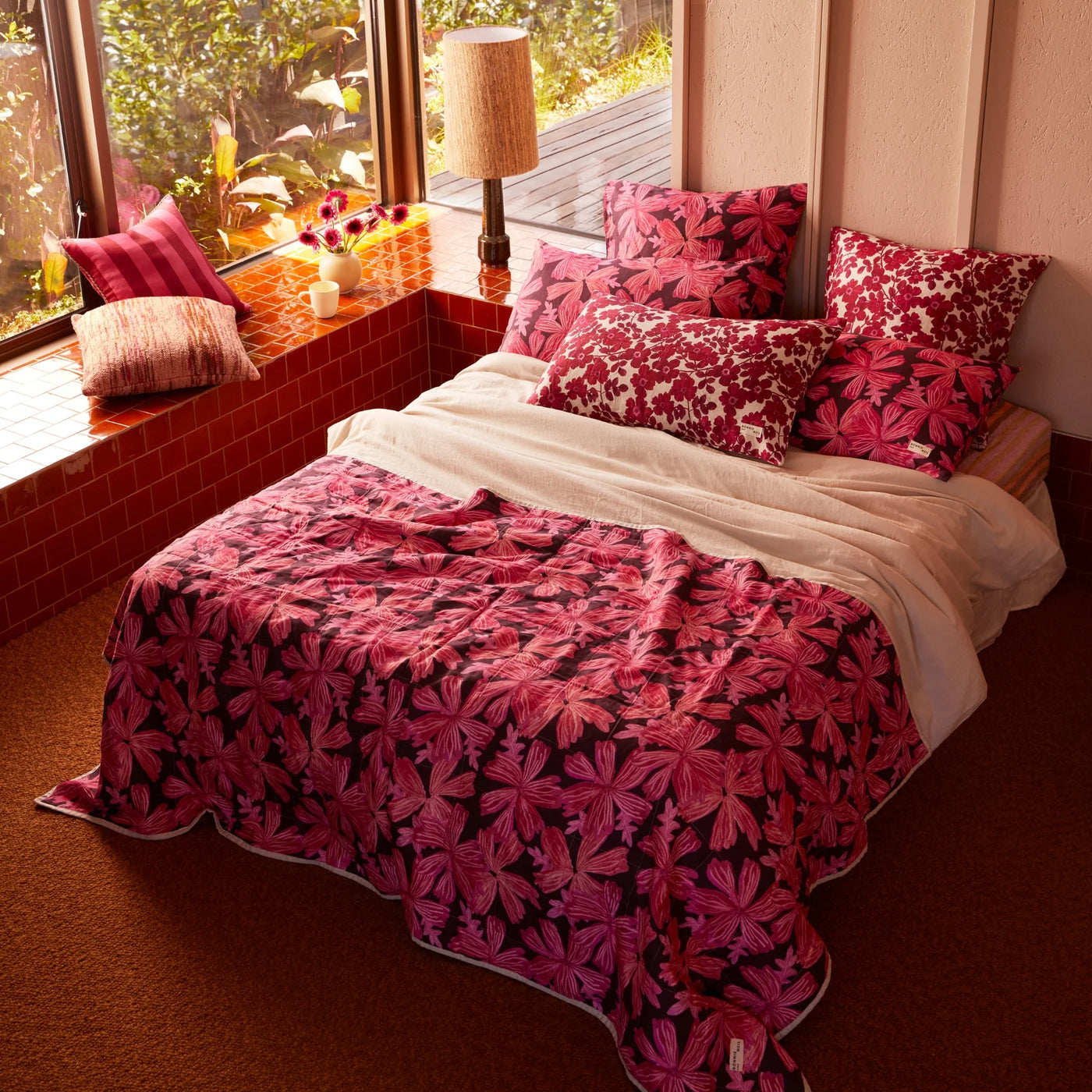 Bed with pink floral quilted throw, pink floral cushion, and pillow with pink floral pillowcase
