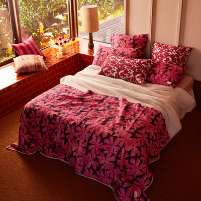 bed with  pink floral quilted throw and pink floral cushion and pillow with pink floral pillow case