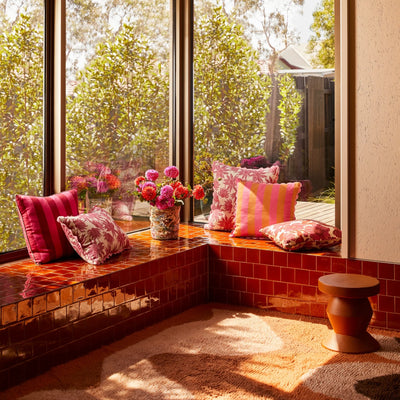 Bench beside the window seal with pink flannel flower and bold stripe cushion