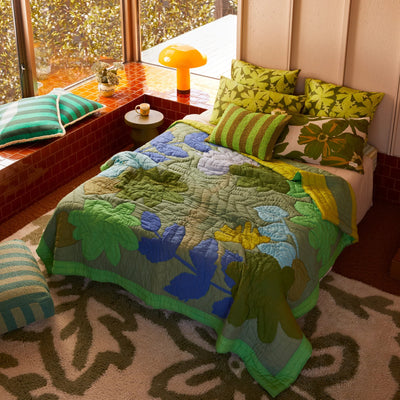 Bed with floral quilted throw and stripe cushion and pillow with printed floral pillowcase