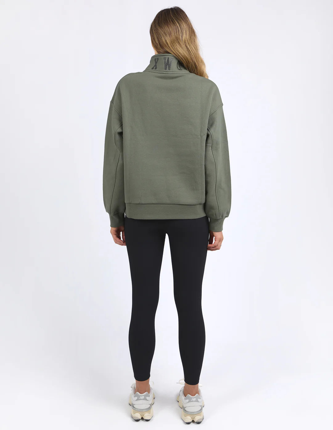 Woman facing the back wearing college zip crew khaki and black leggings
