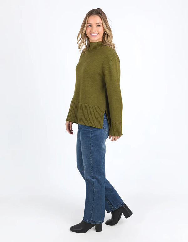 Woman wearing the Jude Knit in Olive Green and light denim pants
