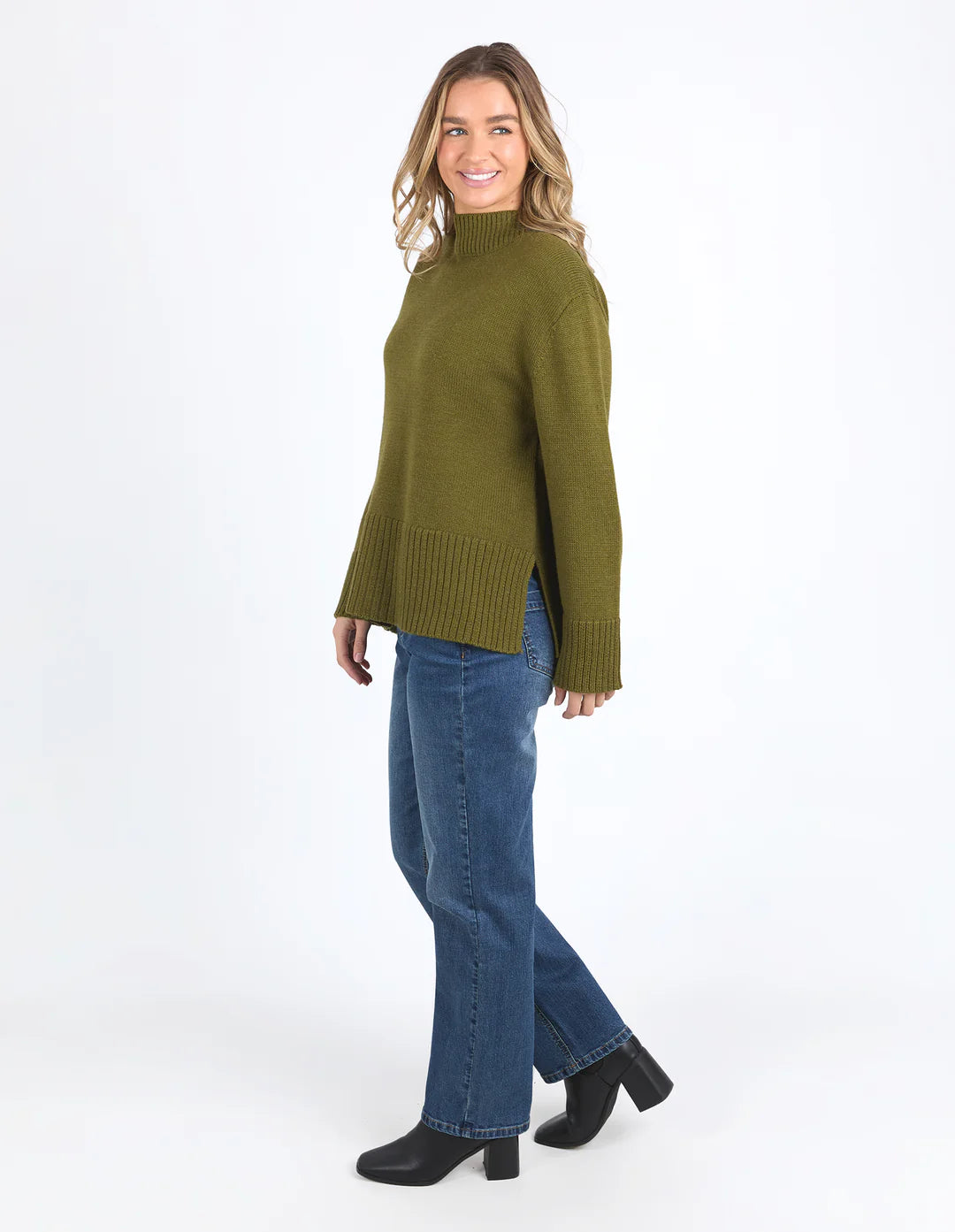 Woman wearing the Jude Knit in Olive Green and light denim pants