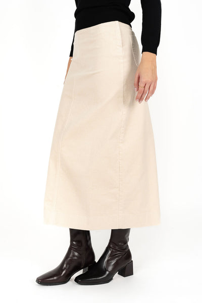 Woman wearing black long sleeve top and Billie Cord Maxi Skirt in Vanilla and black boots side view