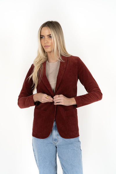 Woman wearing cream top with Blondie Jacket in Rust colour and light blue denim pants