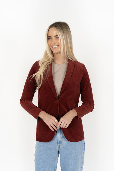 Woman wearing cream top with Blondie Jacket in Rust colour and light blue denim pants