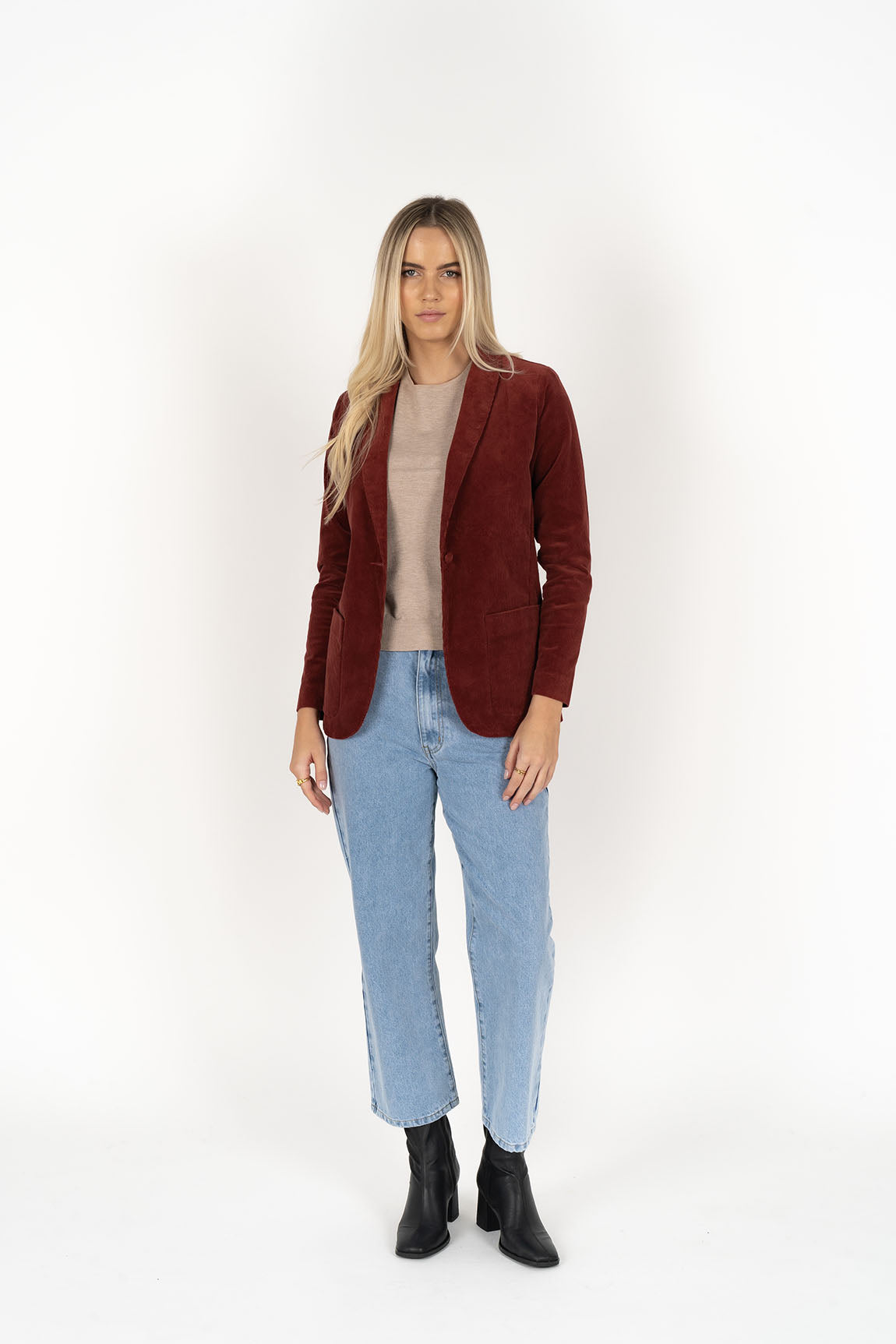 Woman wearing cream top with Blondie Jacket in Rust colour and light blue denim pants