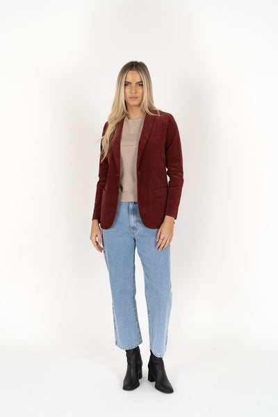 Woman wearing cream top with Blondie Jacket in Rust colour and light blue denim pants