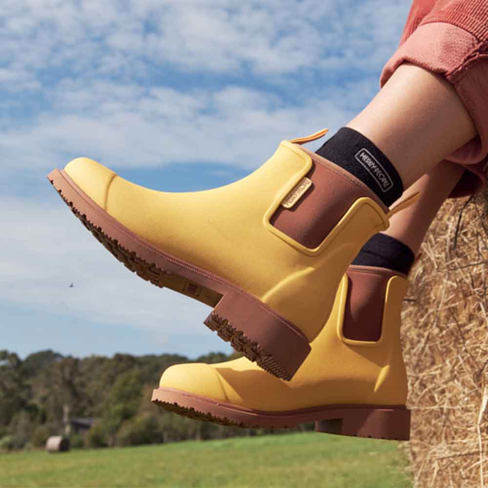 showing only the leg of a woman sitting wearing pants and Bobbi Boot - Sunflower Yellow