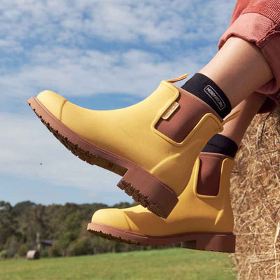 showing only the leg of a woman sitting wearing pants and Bobbi Boot - Sunflower Yellow
