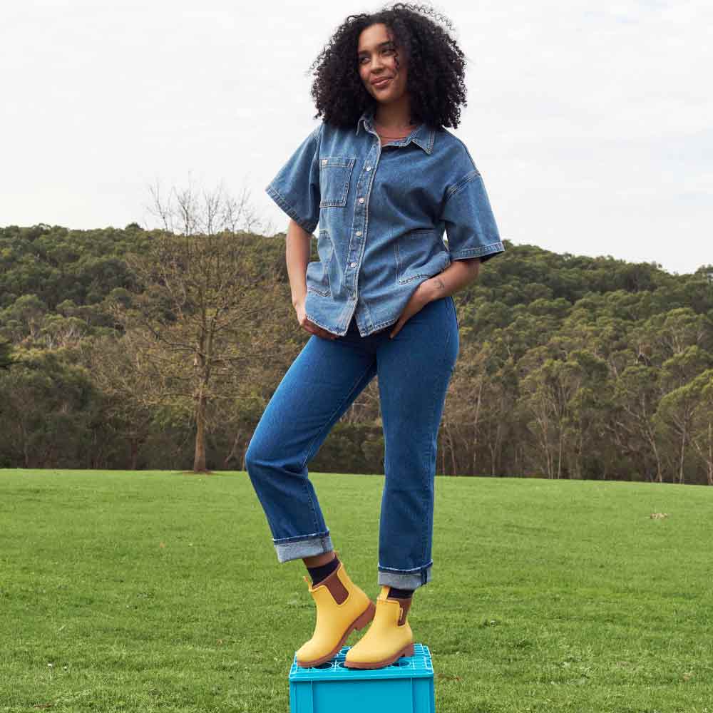 standing woman wearing denim top and pants and Bobbi Boot - Sunflower Yellow