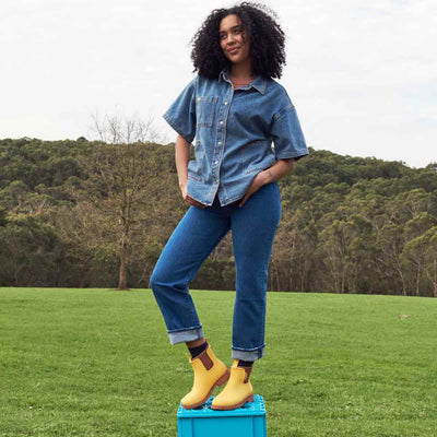 standing woman wearing denim top and pants and Bobbi Boot - Sunflower Yellow