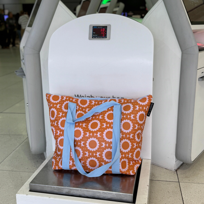 zip medium tote bag in geo floral on a luggage scale at an airport.