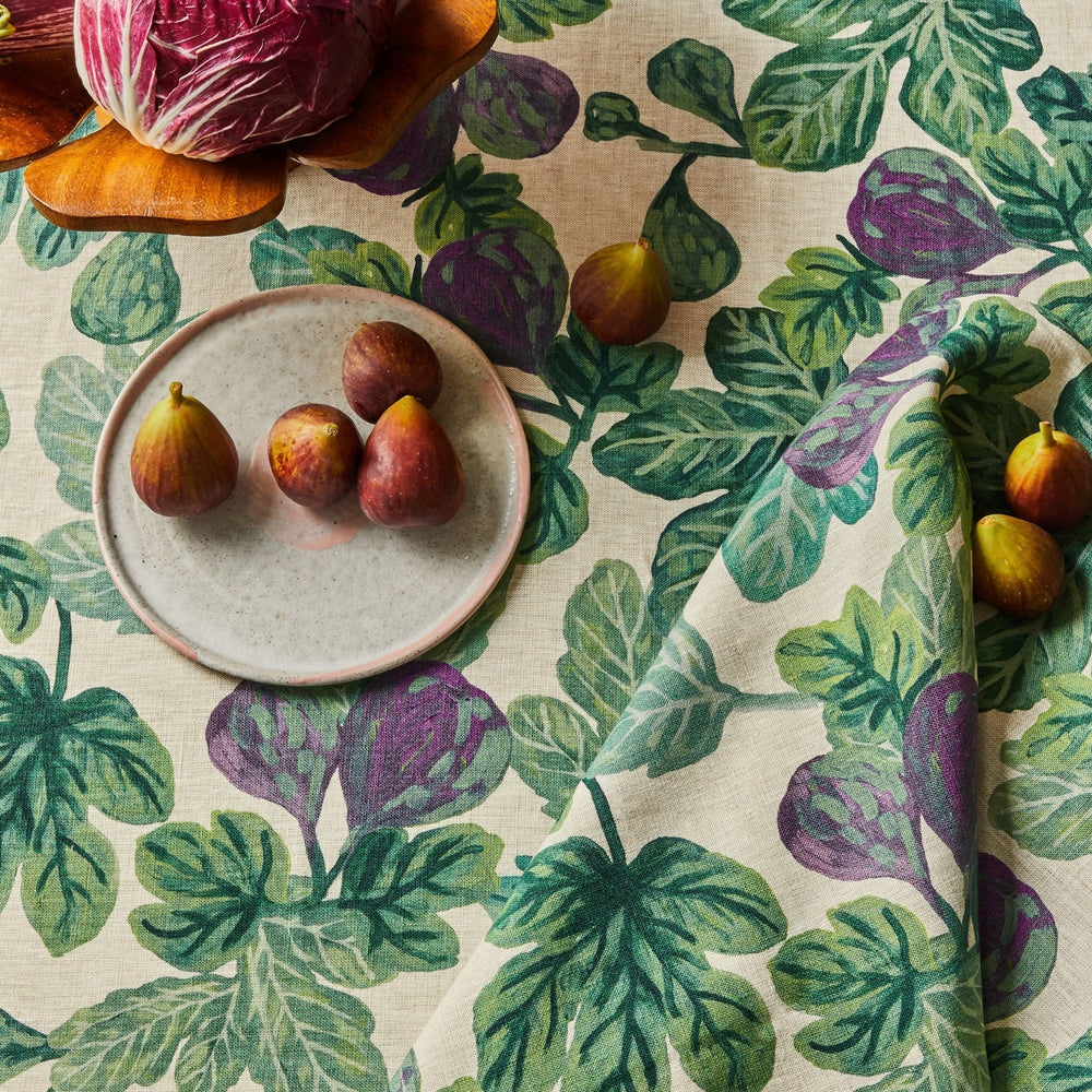 Figs resting on a fig-patterned tablecloth and figgy green napkins set