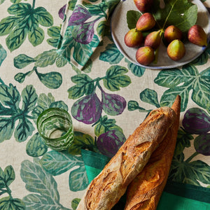 Plate of figs, green glass, and baguettes on a fig-patterned tablecloth and figgy green napkins set of four