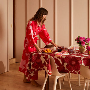 Woman in a red robe setting a table with a red floral tablecloth and leon cerise napkins set of four