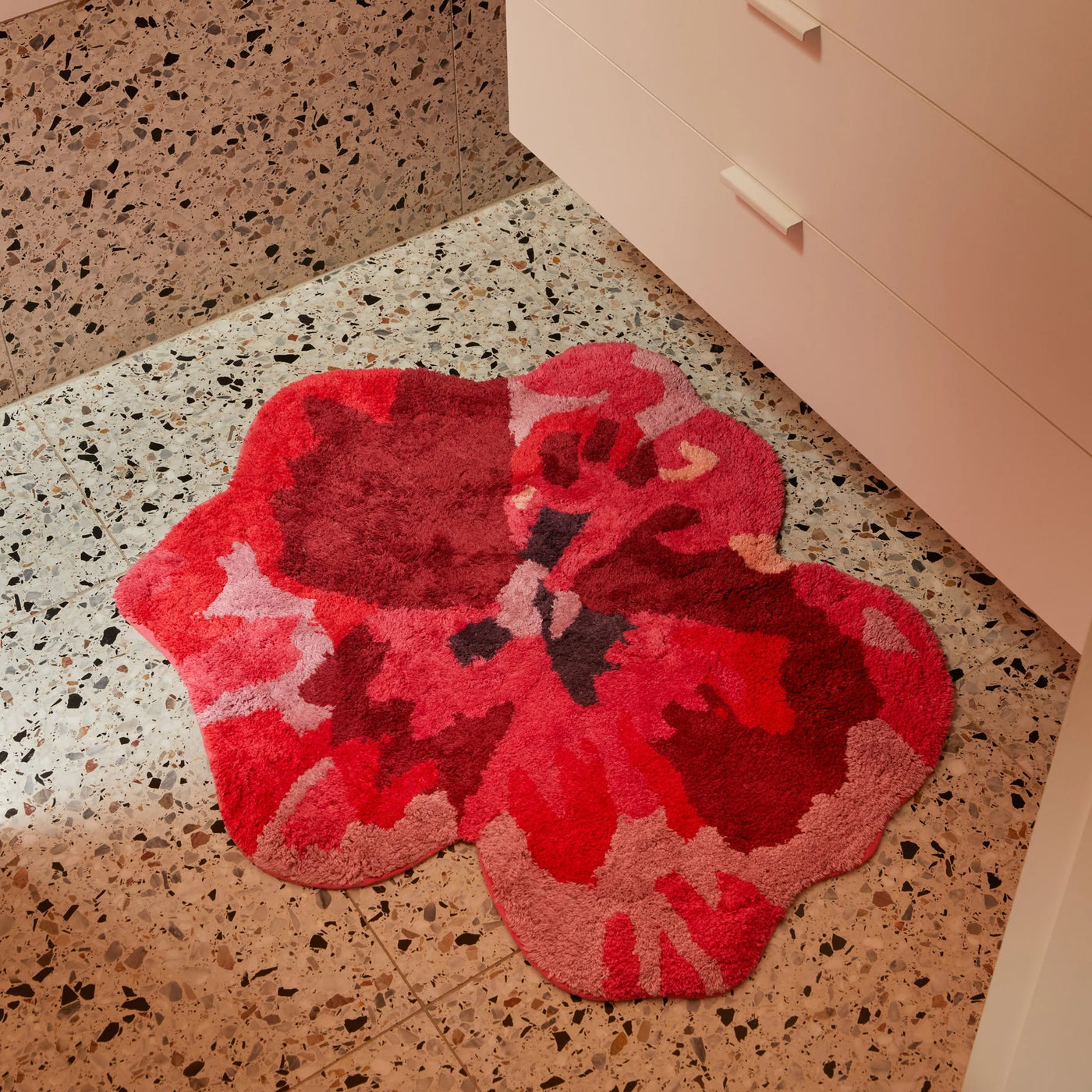 pansy bath mat placed on terrazzo bathroom floor next to a white cabinet with drawers