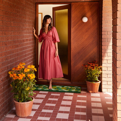 woman standing the in the door with Pansy Green Long Door Mat