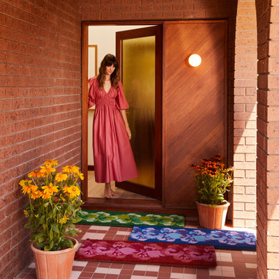 woman in the house entrance with different colour long door mat - green, blue, pink