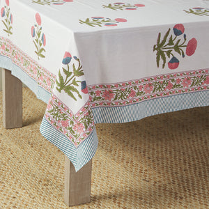 table with canvas and sasson tableau tablecloth in Pink features a large Mughal poppy print in hues of pinks, greens and blues on a white cotton base, finished with a beautifully ornate flowing border and striped edge.