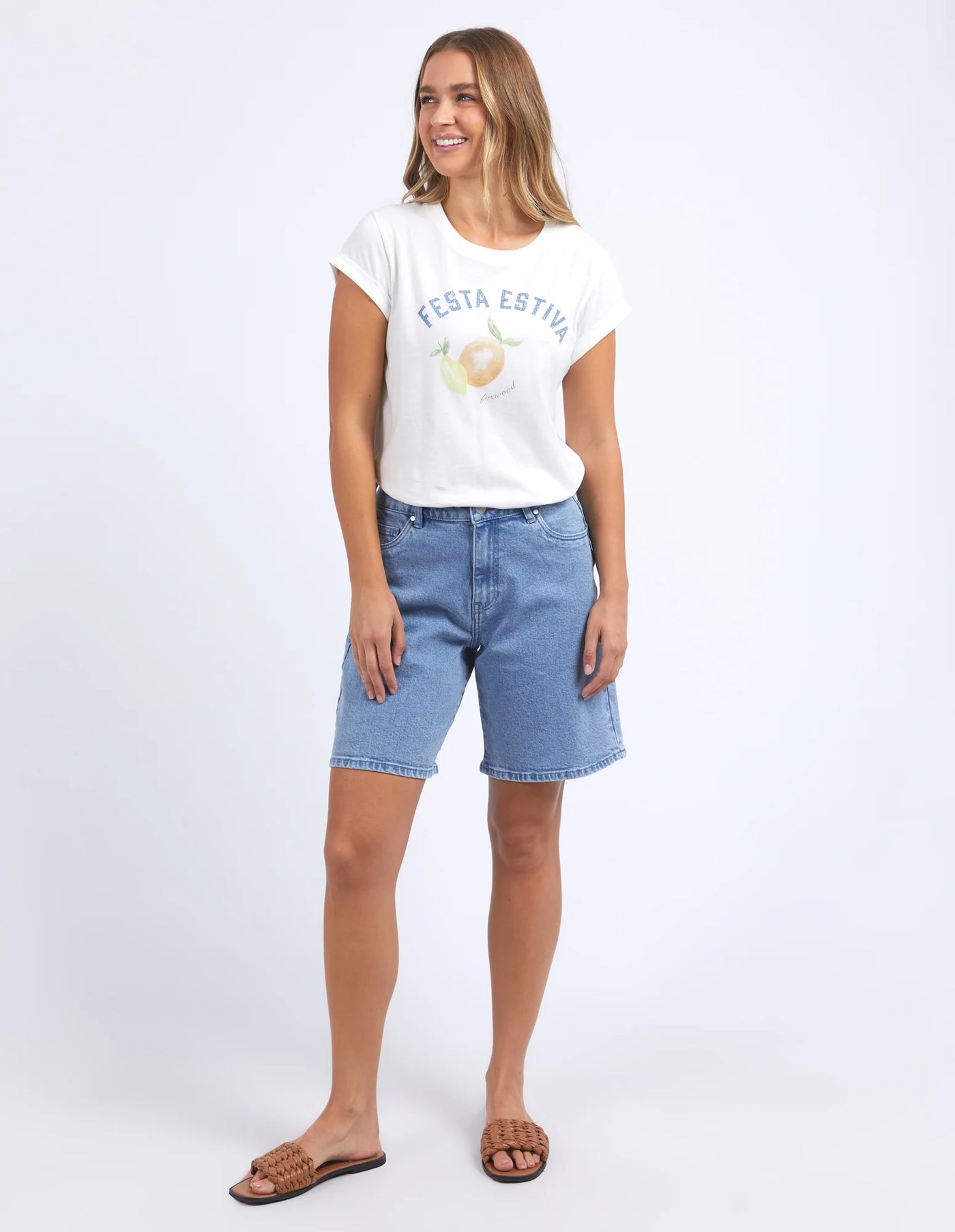 woman wearing foxwood italian summer tee vintage in white, denim short, and brown slip on slippers