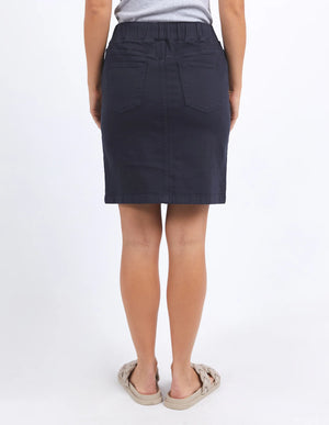 woman wearing grey sleeveless top, foxwood rio skirt dark sapphire, and slip on slippers