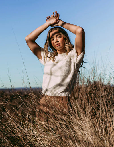 Woman in the field wearing Blair Short Sleeve Knit Vintage White and brown pants