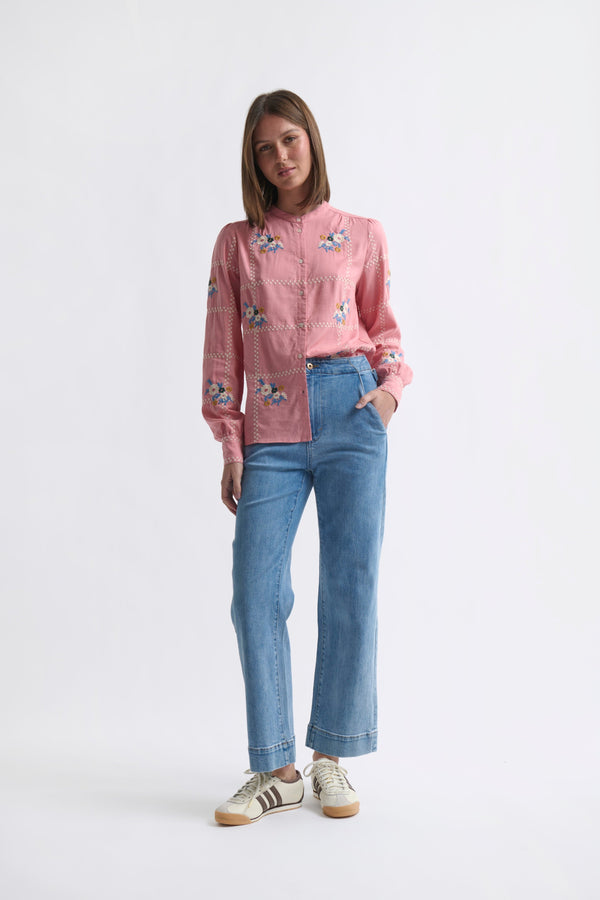 Kireina Carol Shirt in Musk Pink – full-body ecom shot, model wearing the floral-embroidered musk pink shirt tucked into wide-leg blue jeans with white sneakers, straight-on view on a white background