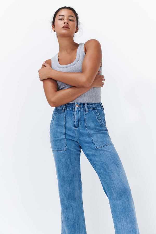 Upper body shot of Celeste Pant 70s Blue with arms crossed showing zip fly and front patch pockets