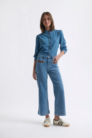 Full-length ecom shot of Freya Jean Leather Pocket 70s Blue with denim top and sneakers, PU leather pockets visible