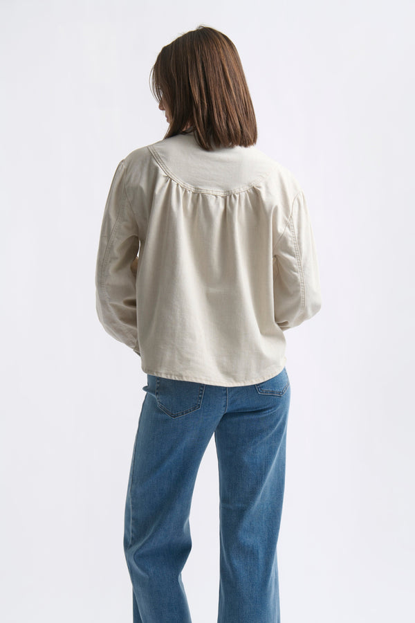 Back view ecom shot of Kelly Shirt Sand showing relaxed back yoke and puffed sleeves styled with wide-leg jeans on white background