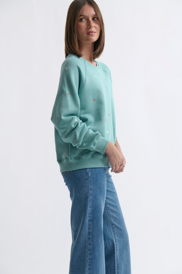 Side profile ecom shot of Patti Sweatshirt Daisy Mint Green showing raglan sleeve and relaxed silhouette styled with jeans on white background
