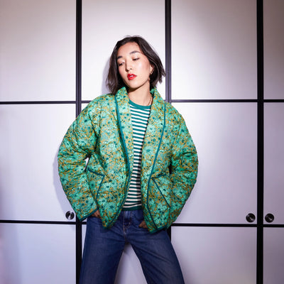 Woman wearing green and white stripe top and dark blue denim pants and Evette Quilted Jacket in Martini