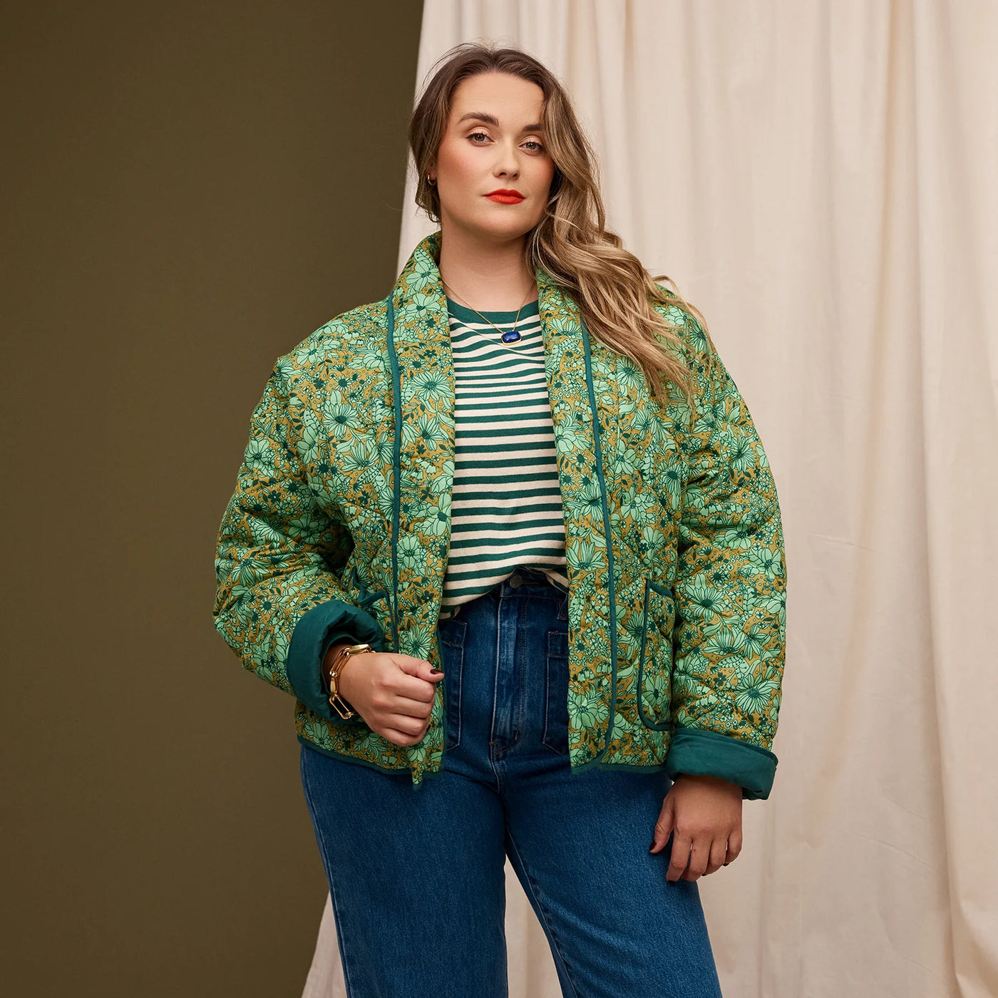 Plus size woman wearing green and white stripe top and dark blue denim pants and Evette Quilted Jacket in Martini
