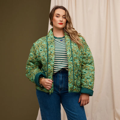 Plus size woman wearing green and white stripe top and dark blue denim pants and Evette Quilted Jacket in Martini