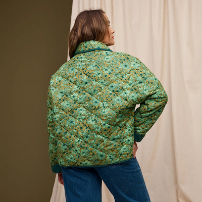 Woman facing the back wearing dark blue denim pants and Evette Quilted Jacket in Martini