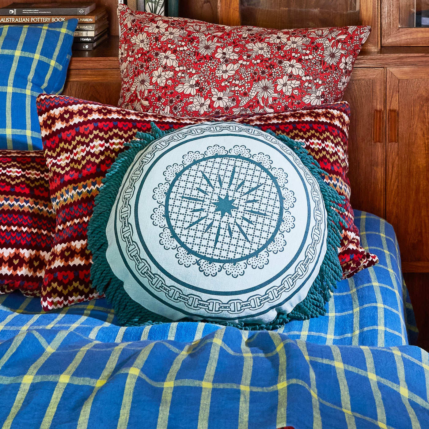 Bed with printed pillow and blue bed cover and Manville Fringe Cushion