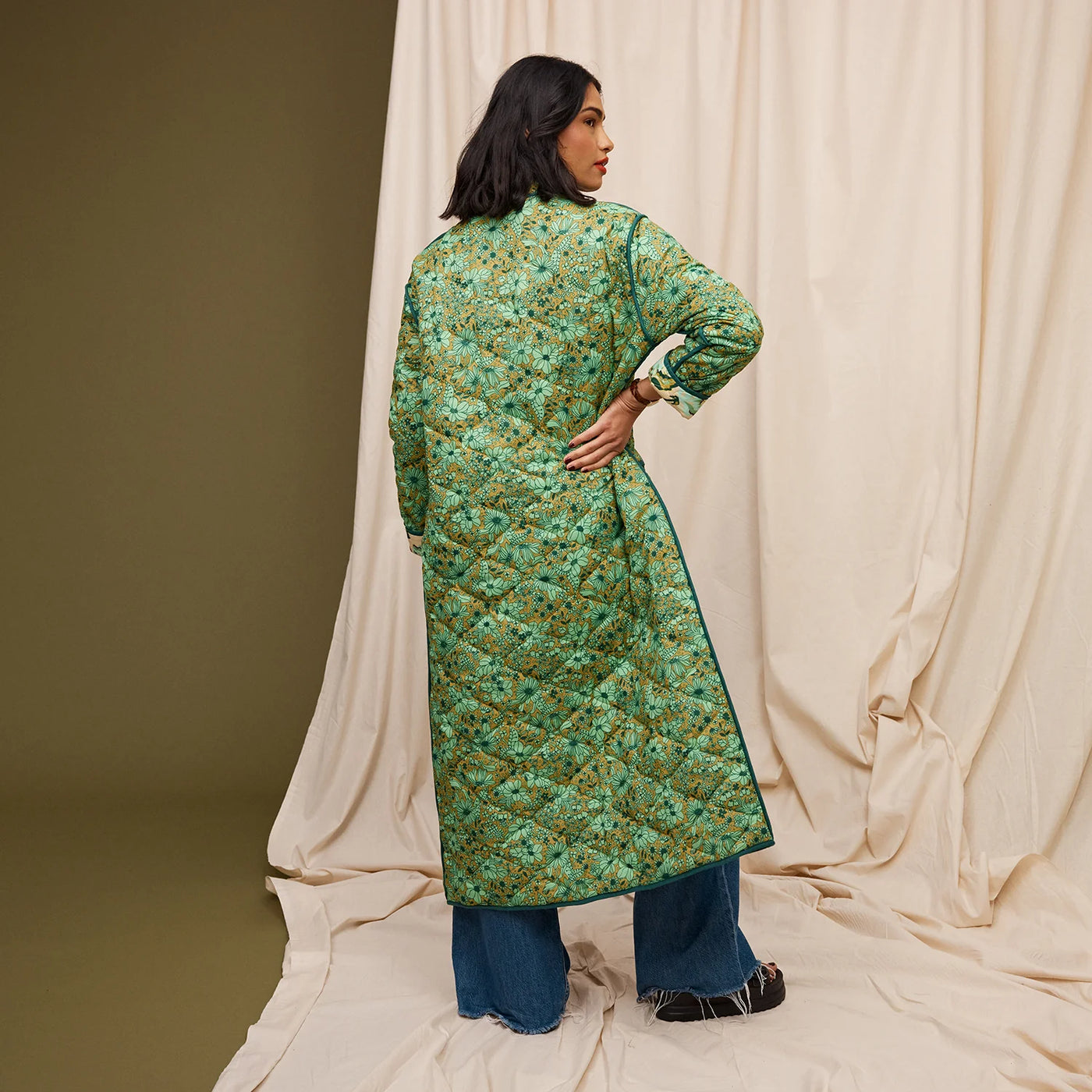 Woman wearing Margot Quilted Coat and dark denim pants facing the back