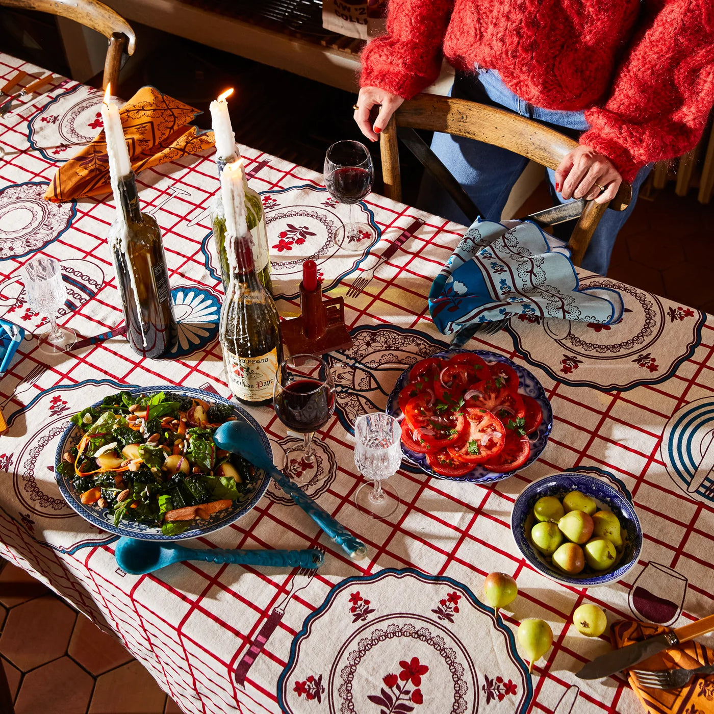 Candlelit dining table set with remi table cloth with wine, food, and tableware
