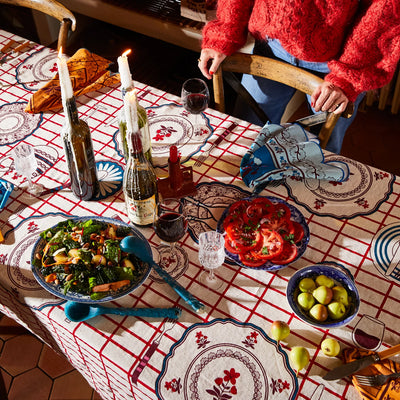 Candlelit dining table set with remi table cloth with wine, food, and tableware
