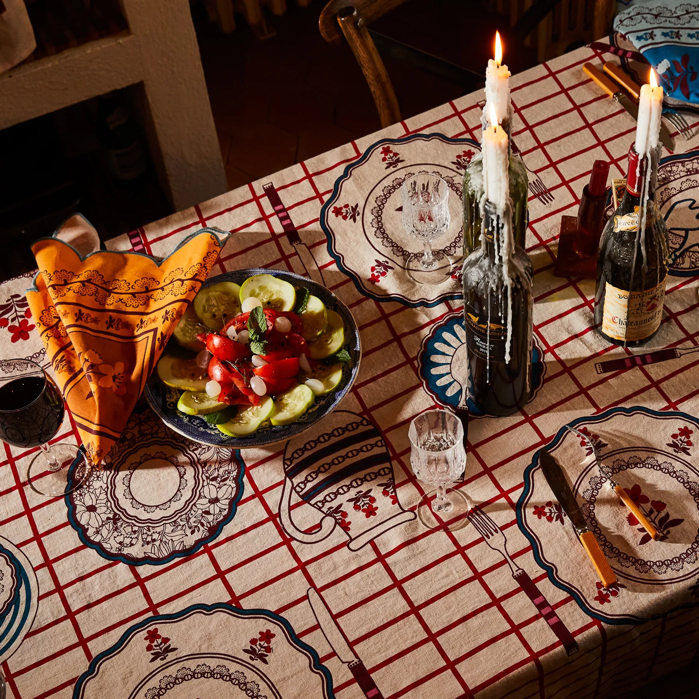 Candlelit dining table set with remi table cloth with wine, food, and tableware