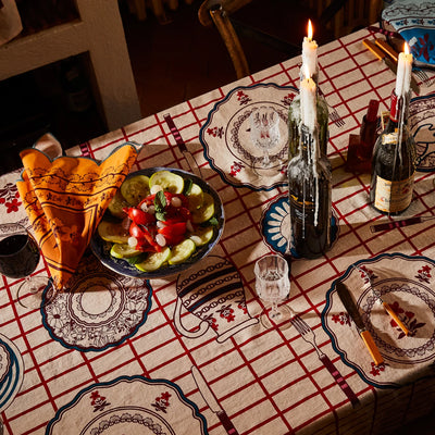 Candlelit dining table set with remi table cloth with wine, food, and tableware