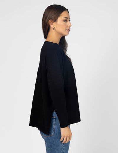 woman facing the side wearing Halle Knit Top - Black and denim pants