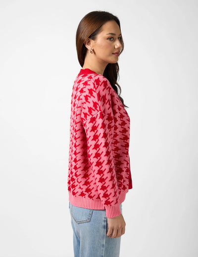 woman wearing Xanthe Houndstooth Cardigan - Red & Candy and light denim pants facing side view
